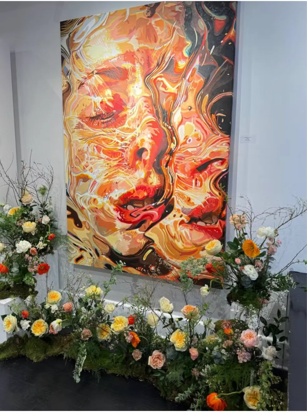 Floral installation beneath a large painted portrait in a gallery