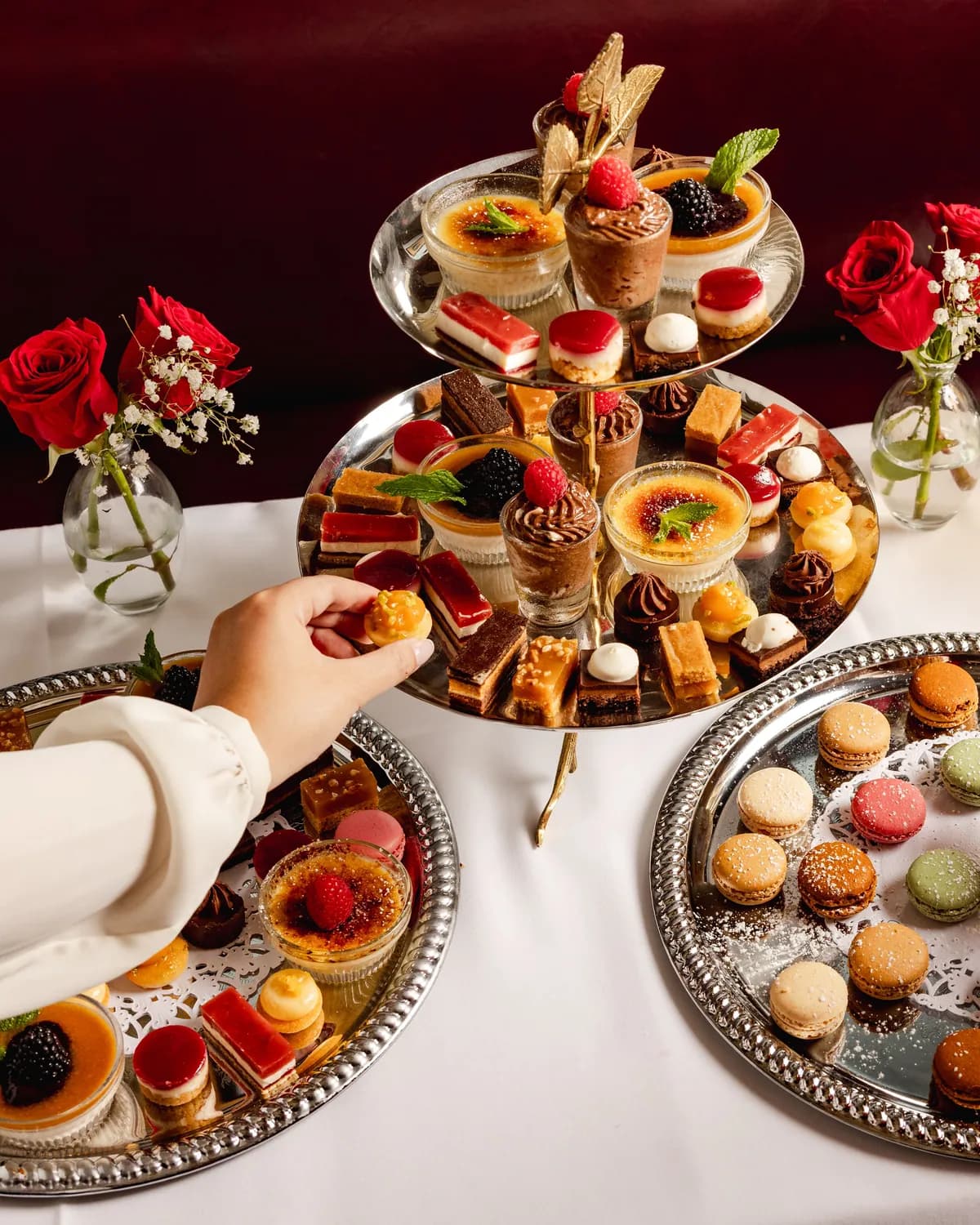 Guests reaching for macarons and pastries from a tiered stand, champagne alongside